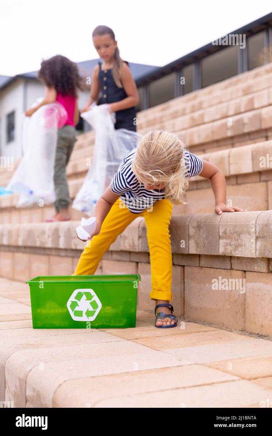 Les écolières élémentaires multiraciales collectent des déchets plastiques sur les étapes de construction de l'école Banque D'Images