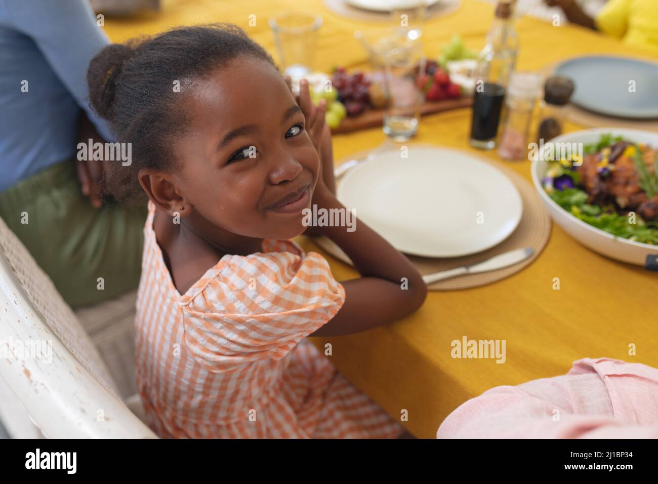 Fille souriante afro-américaine prenant le déjeuner avec la famille à table le jour de l'action de grâce Banque D'Images