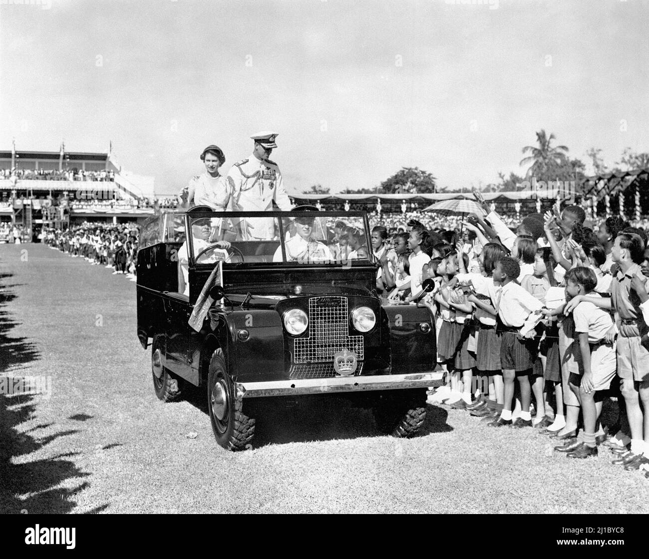 RETRANSMIS MODIFIANT LA LÉGENDE DISANT QU'IL S'AGIT D'Un LAND ROVER SIMILAIRE ET PAS LE MÊME PHOTO de dossier datée du 25/11/1953 de la Reine et du duc d'Édimbourg descendre les lignes de 20 000 jeunes dessinés pour les accueillir à Sabina Park, Kingston, lors de leur visite en Jamaïque. Le duc et la duchesse de Cambridge ont utilisé un Land Rover similaire lorsqu'ils ont assisté à la cérémonie inaugurale de Commissioning Parade pour le personnel de service de partout dans les Caraïbes, qui a récemment terminé le programme de formation des officiers de l'Académie militaire des Caraïbes, à Kingston, en Jamaïque, dans le cadre de leur tournée dans les Caraïbes. Date de publication : Banque D'Images
