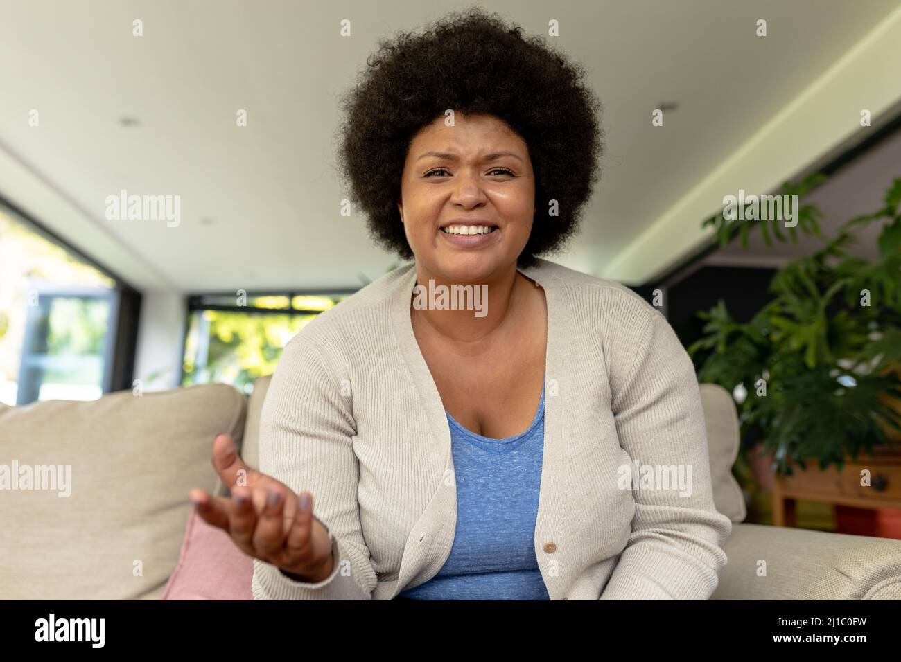 Portrait d'une femme mi-adulte afro-américaine souriante en train de gesturer lors d'une vidéoconférence à la maison Banque D'Images