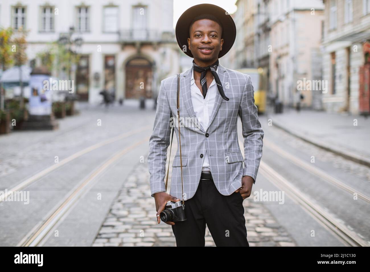 Beau homme africain élégant costume et chapeau posé sur la rue de ville  avec photo rétro dans les mains. Les jeunes garçons passent le week-end  pour voyager Photo Stock - Alamy