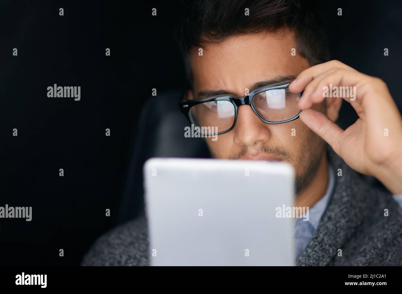 Nouveautés sur les réseaux sociaux. Photo d'un jeune homme portant des lunettes à l'aide d'une tablette numérique dans l'obscurité. Banque D'Images