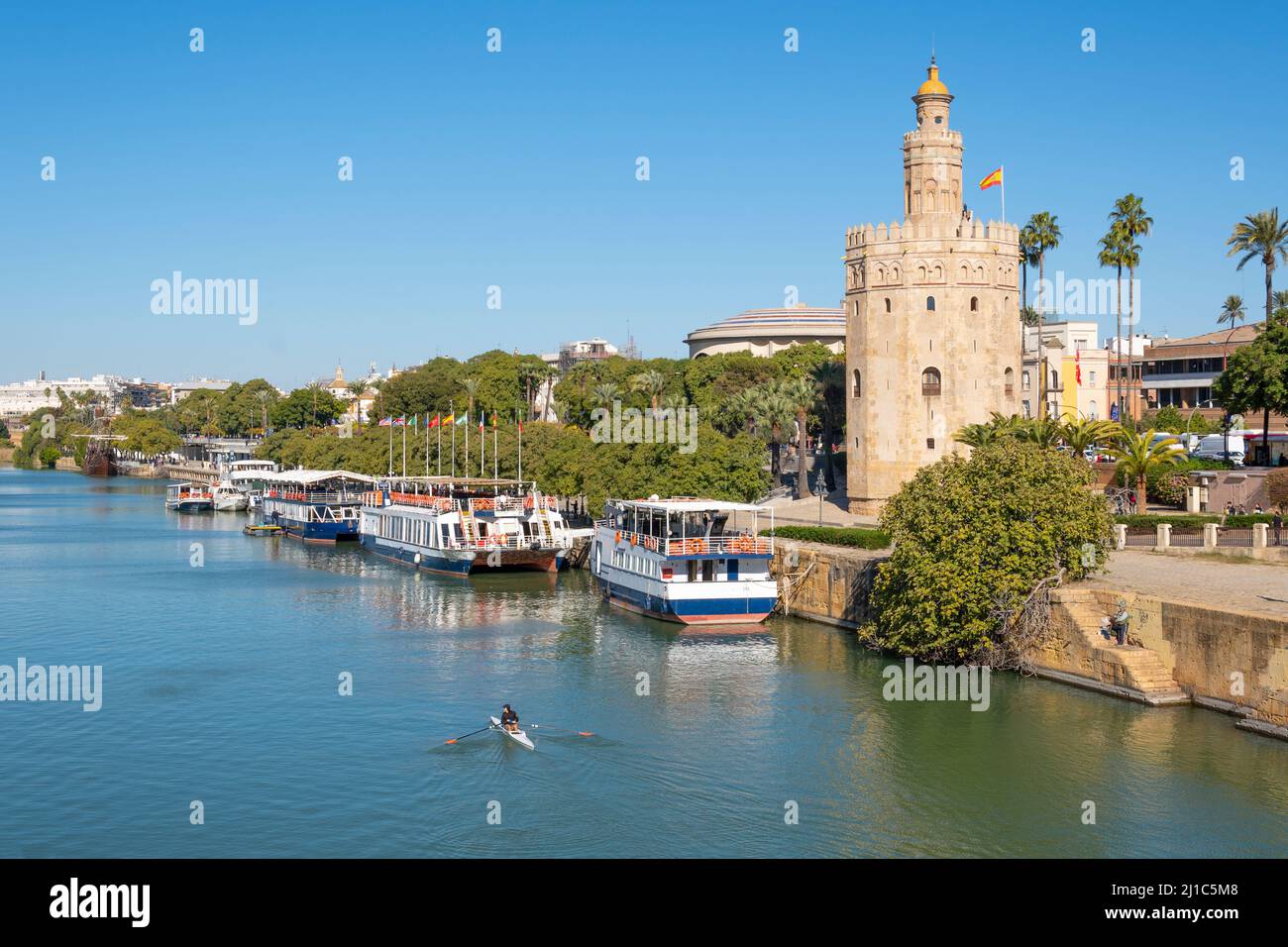 La rivière Guadalquivier traverse le centre historique de Séville, en Espagne, avec des bateaux touristiques le long de la tour Torre del Oro. Banque D'Images