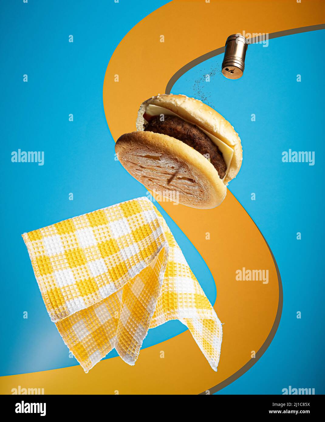 Vue sur un délicieux hamburger volant avec serviette en fond bleu et orange Banque D'Images