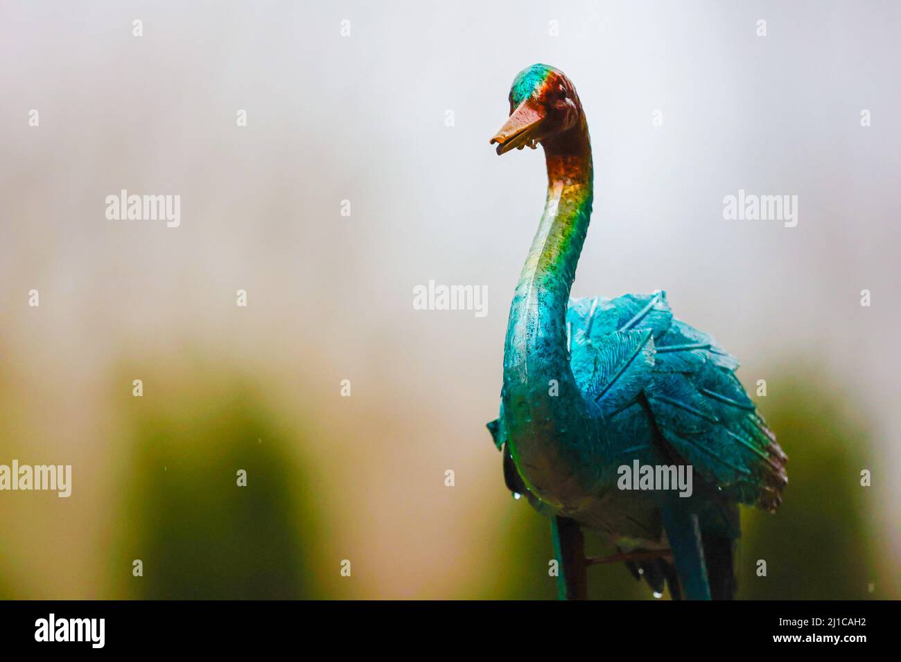 Un arrière-plan complètement flou de la nature avec une décoration de cour en métal, un oiseau, au premier plan. Banque D'Images