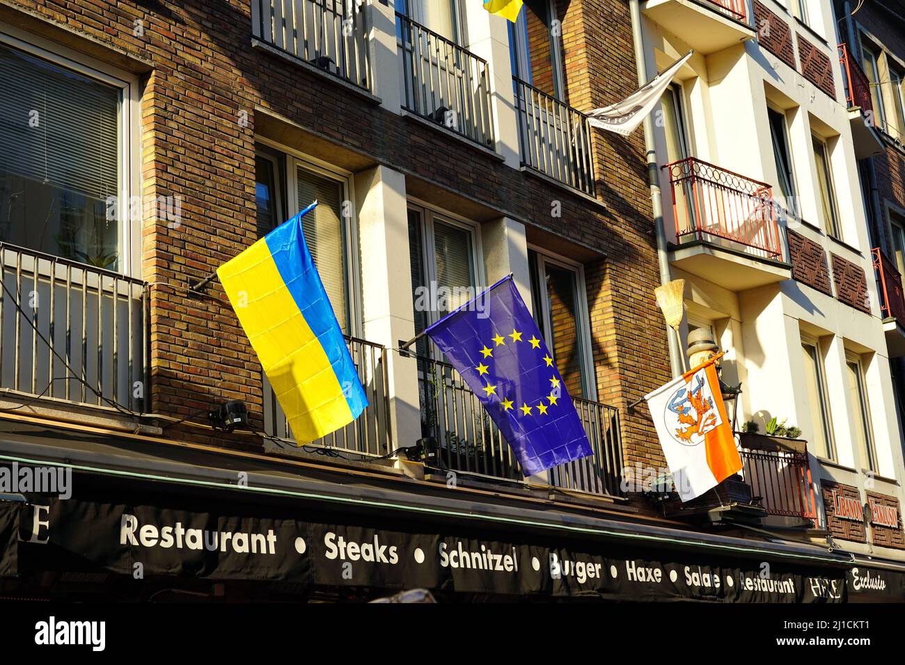 Gros plan de différents drapeaux locaux et internationaux (drapeau de l'Ukraine, drapeau de l'UE, drapeau de Düsseldorf) devant un restaurant dans la vieille ville de Düsseldorf/Allemagne. Banque D'Images