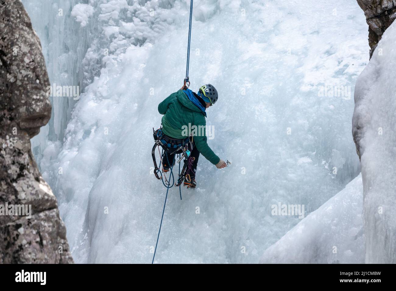 Un grimpeur à glace se visse dans un ancrage à vis de glace alors qu'il descend un mur de glace de 160 pi de haut dans le parc de glace d'Ouray, Colorado, Banque D'Images