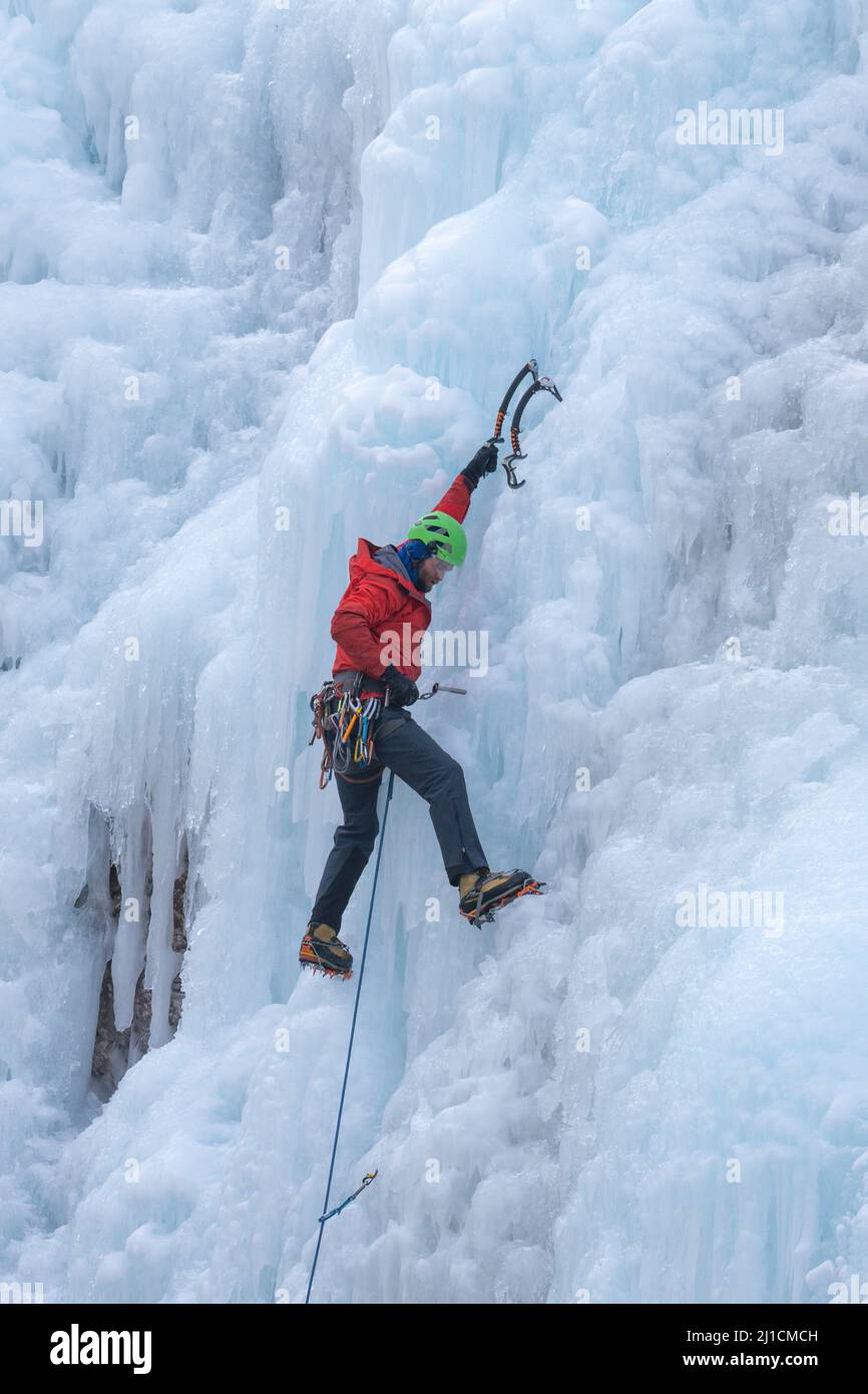 Un grimpeur à glace se visse dans un ancrage à vis de glace alors qu'il mène monte un mur de glace de 160 pi de haut dans le parc de glace d'Ouray, Colorado. Un grimpeur principal n'a pas de t Banque D'Images