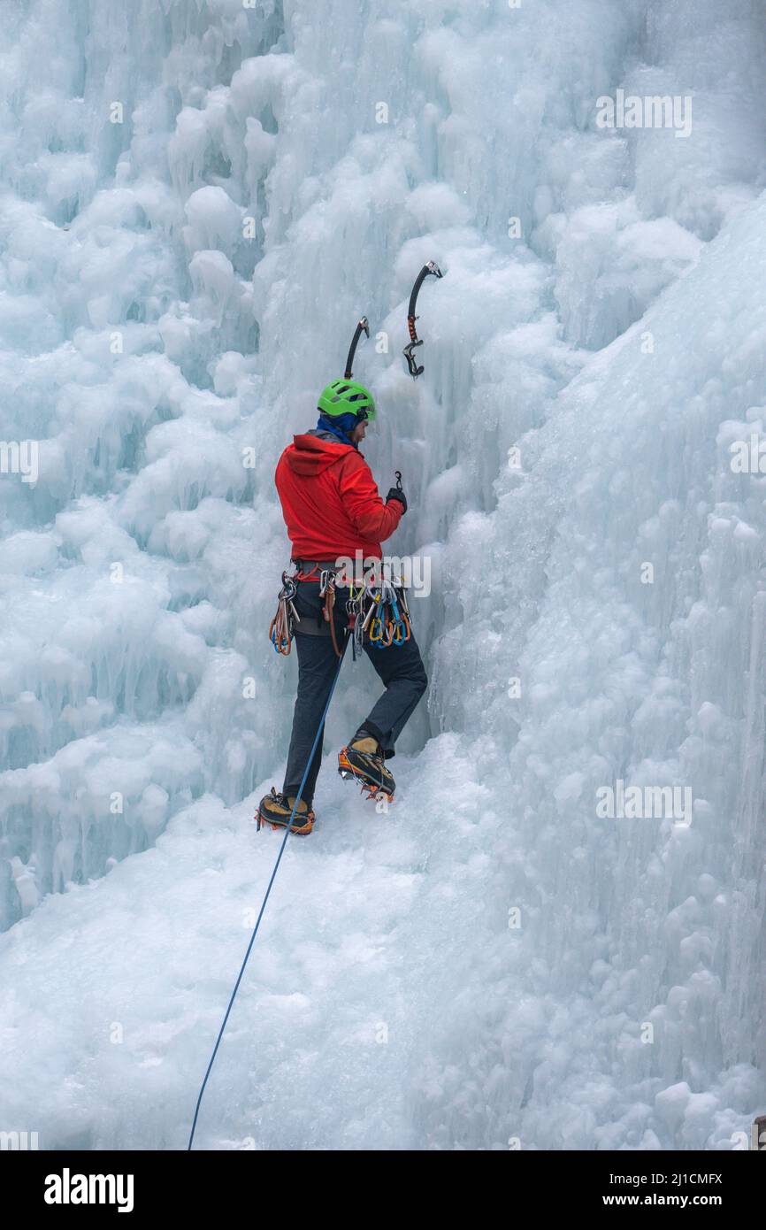 Un grimpeur à glace se visse dans un ancrage à vis de glace alors qu'il mène monte un mur de glace de 160 pi de haut dans le parc de glace d'Ouray, Colorado. Un grimpeur principal n'a pas de t Banque D'Images