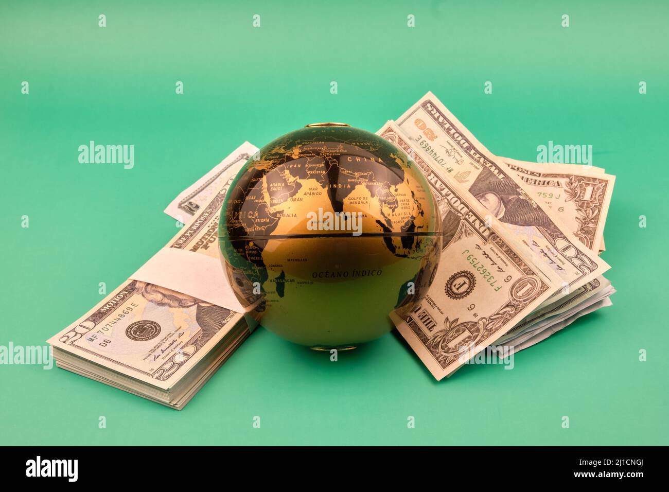 Un tas de dollars et une boule du monde avec un fond vert. Concept l'argent déplace le monde. Photographie au format horizontal. Copier l'espace. Banque D'Images