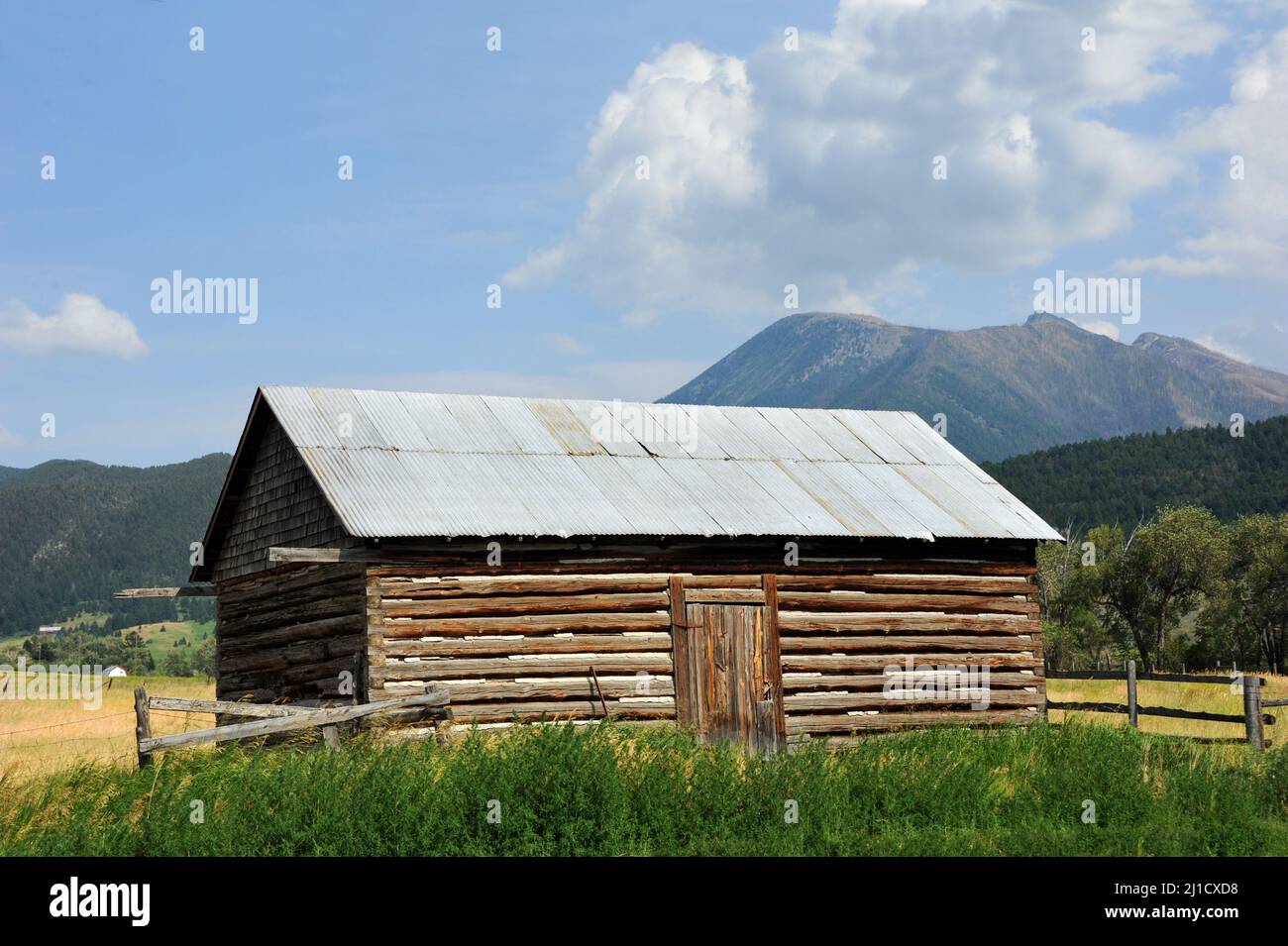 Gros plan d'une cabane en rondins entourée d'un pré, d'herbe et des monts Absaroka du Montana. Banque D'Images
