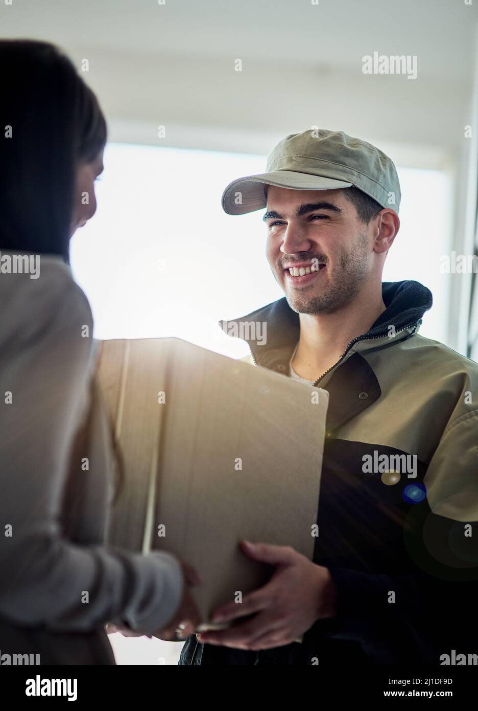 Votre livraison le lendemain est arrivée. Photo rognée d'un coursier faisant une livraison à un client à sa maison. Banque D'Images