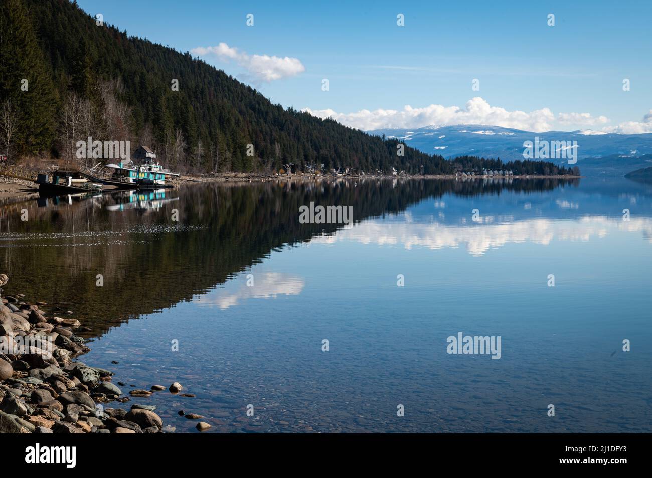 Photo de la forêt, de la plage et de la péniche colorée qui se reflète le long de la rive nord du lac Shuswap dans la région sud-intérieure de la province. Banque D'Images