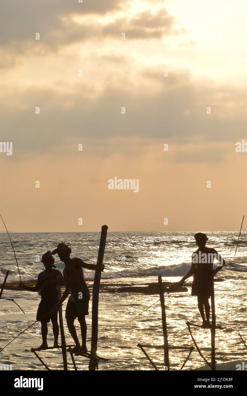 Silhouette de pêcheurs sur pilotis au coucher du soleil, sur la côte sud du Sri Lanka Banque D'Images