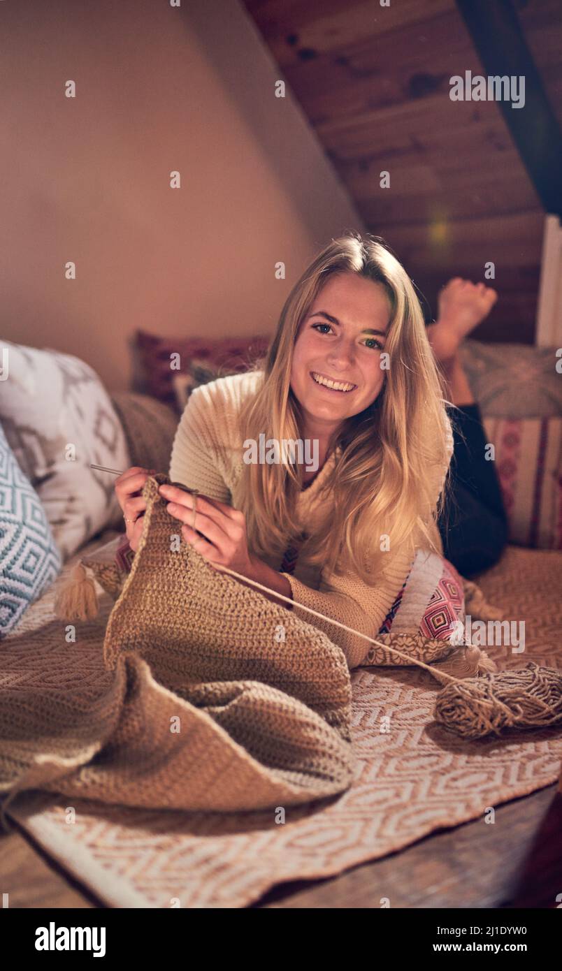 Tricoter n'est pas seulement pour les vieilles dames. Portrait d'une jeune femme triant tout en se relaxant dans sa chambre à la maison. Banque D'Images