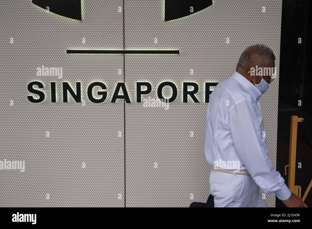 12.11.2021, Singapour, , Singapour - image symbolique pandémie du virus Corona à Singapour. Un homme portant un protège-bouche Corona passe devant un panneau indiquant S. Banque D'Images