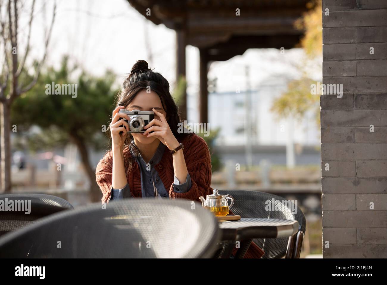 Jeune femme photographiant dans un café-restaurant sur le trottoir - photo de stock Banque D'Images