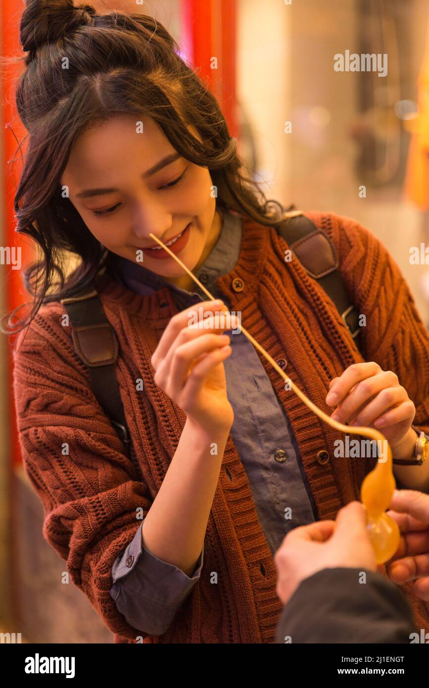 Jeune étudiante d'université se sentant curieuse au sujet de calabash en forme de Tangren à un marché de nuit de Pékin - photo de stock Banque D'Images