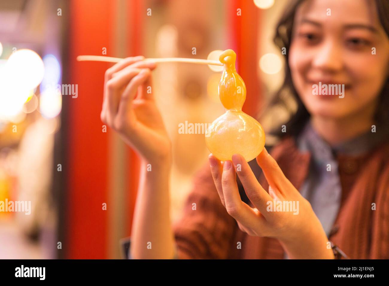 Gros plan. Une jeune étudiante de l'université admirera son propre calabash travaillé Tangren à un marché de nuit à Beijing - photo de stock Banque D'Images