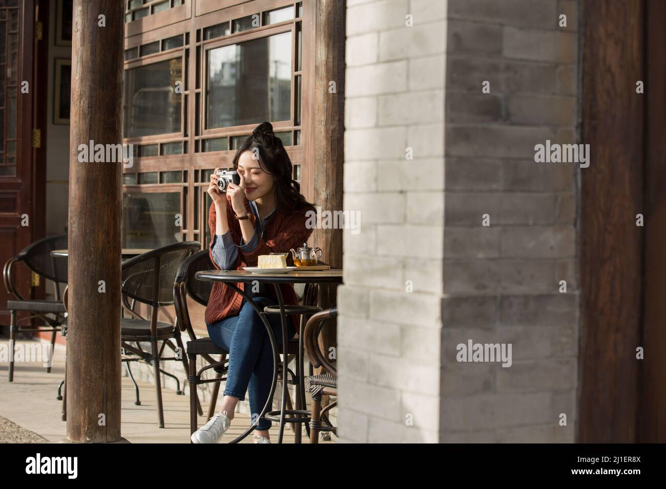 Jeune femme photographiant dans un café-restaurant sur le trottoir - photo de stock Banque D'Images