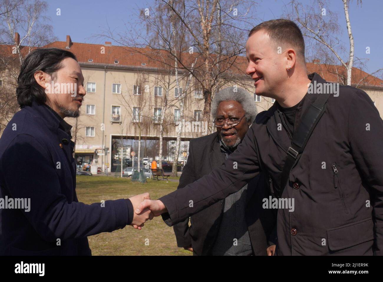 Berlin, Allemagne. 25th mars 2022. L'artiste Kang Sunkoo (l-r), M. S. Mboro de 'Berlin Postkolonial' et Klaus Lederer (Die Linke), sénateur de la Culture, se saluent lors de la présentation de l'œuvre 'volet des limitations' par l'artiste Kang Sunkoo sur Nachtigalplatz. La sculpture en bronze en deux parties, sous forme de drapeau à mi-mât, est visible d'une part dans la salle d'escalier du Forum Humboldt, la moitié supérieure est maintenant temporairement placée dans le quartier africain. Credit: dpa/Alay Live News Banque D'Images