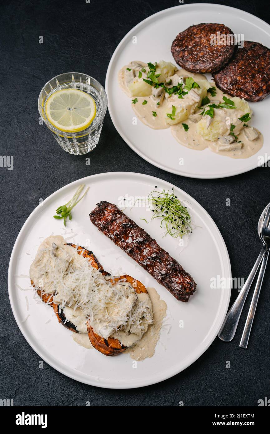 Kebab végétarien à base de plantes avec patate douce, sauce crémeuse et parmesan. Pâtes avec boulettes de viande végétaliennes en arrière-plan. Vue de dessus Banque D'Images