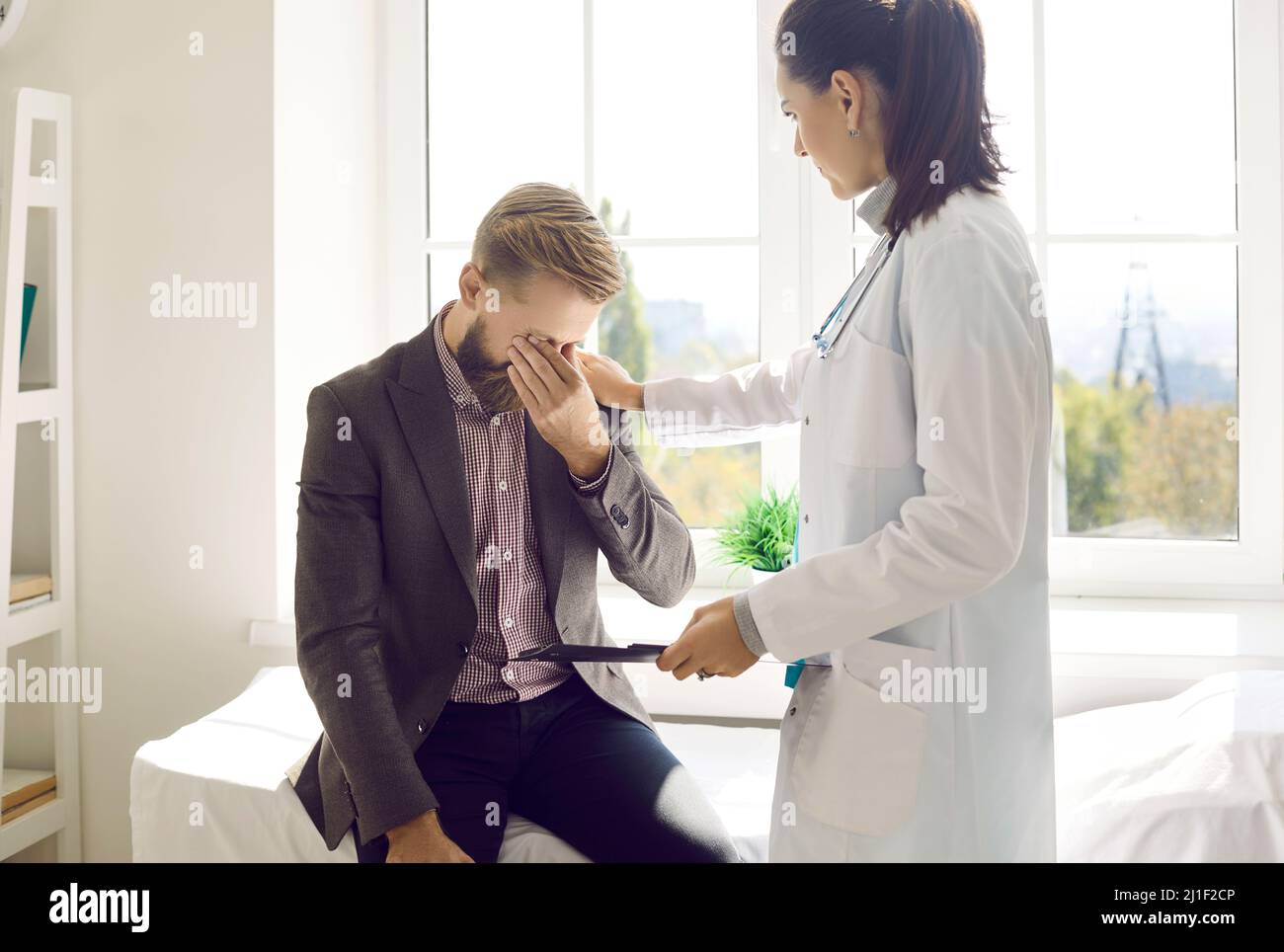 Un médecin ou une infirmière soignante touche l'épaule d'un patient frustré sur rendez-vous médical. Banque D'Images