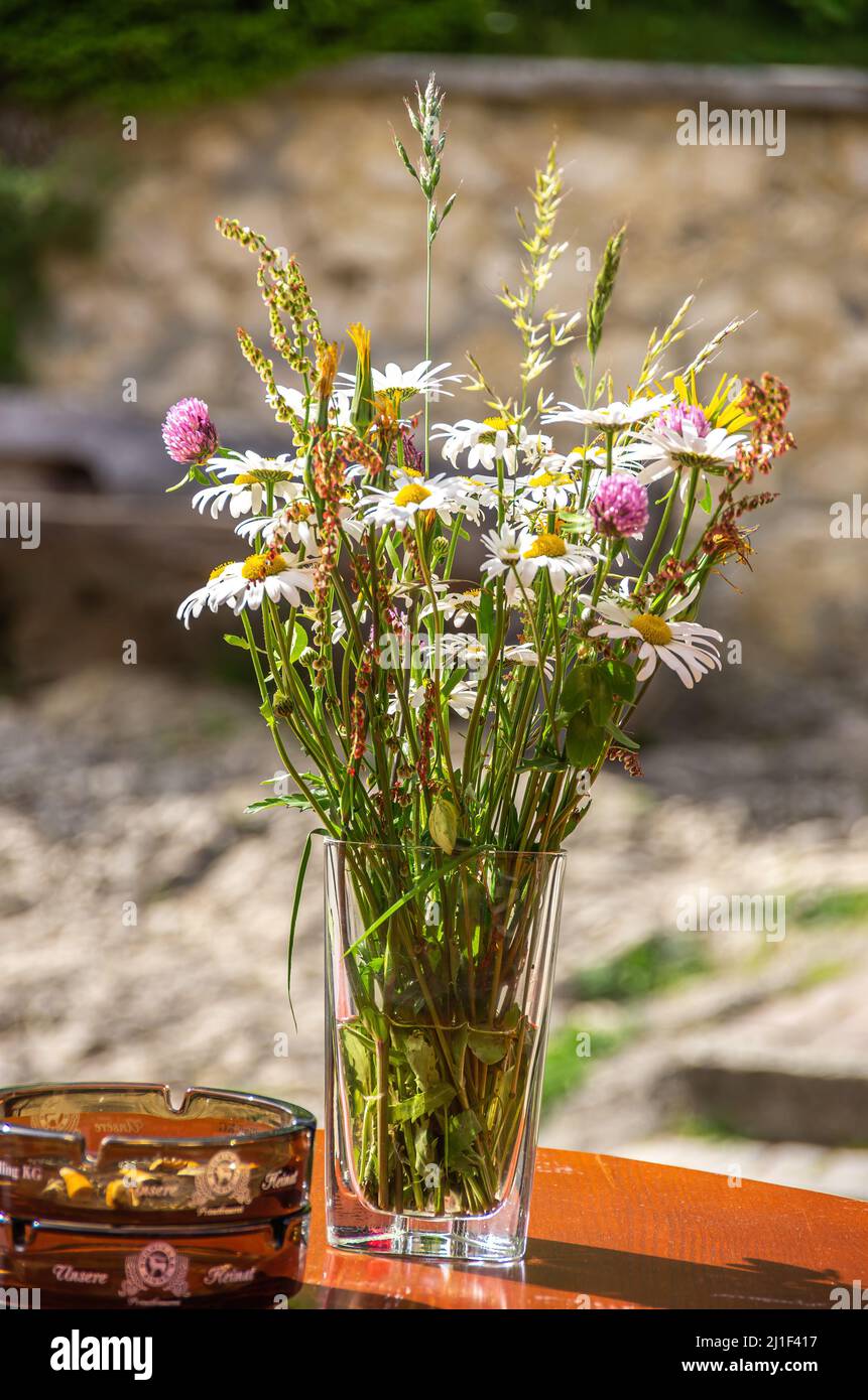 Encore vie de bouquet décoratif de fleurs dans un vase en verre avec cendrier sur une table, Château de Derneck près de Hayingen, Bade-Wurtemberg, Allemagne. Banque D'Images