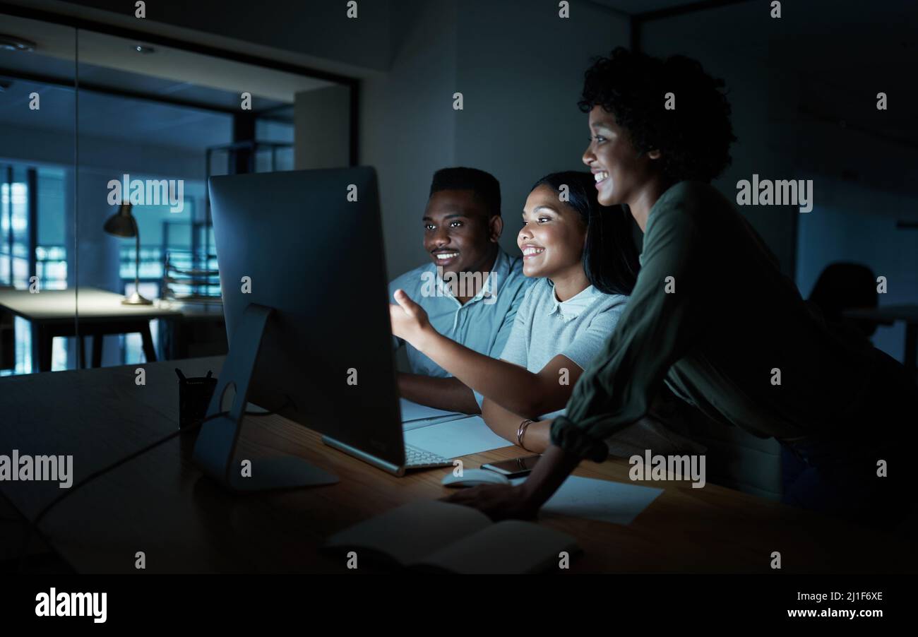 Ceux qui y restent détiennent les clés du succès. Photo d'un groupe de jeunes hommes d'affaires utilisant un ordinateur ensemble pendant une nuit de travail. Banque D'Images