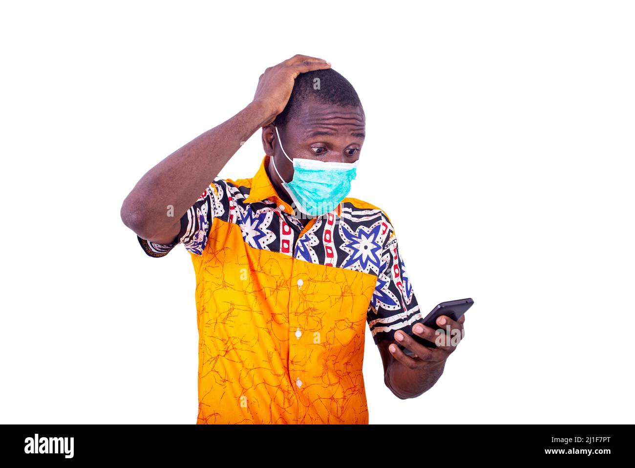 surpris jeune homme portant un masque médical sur son visage regardant le téléphone portable. Banque D'Images