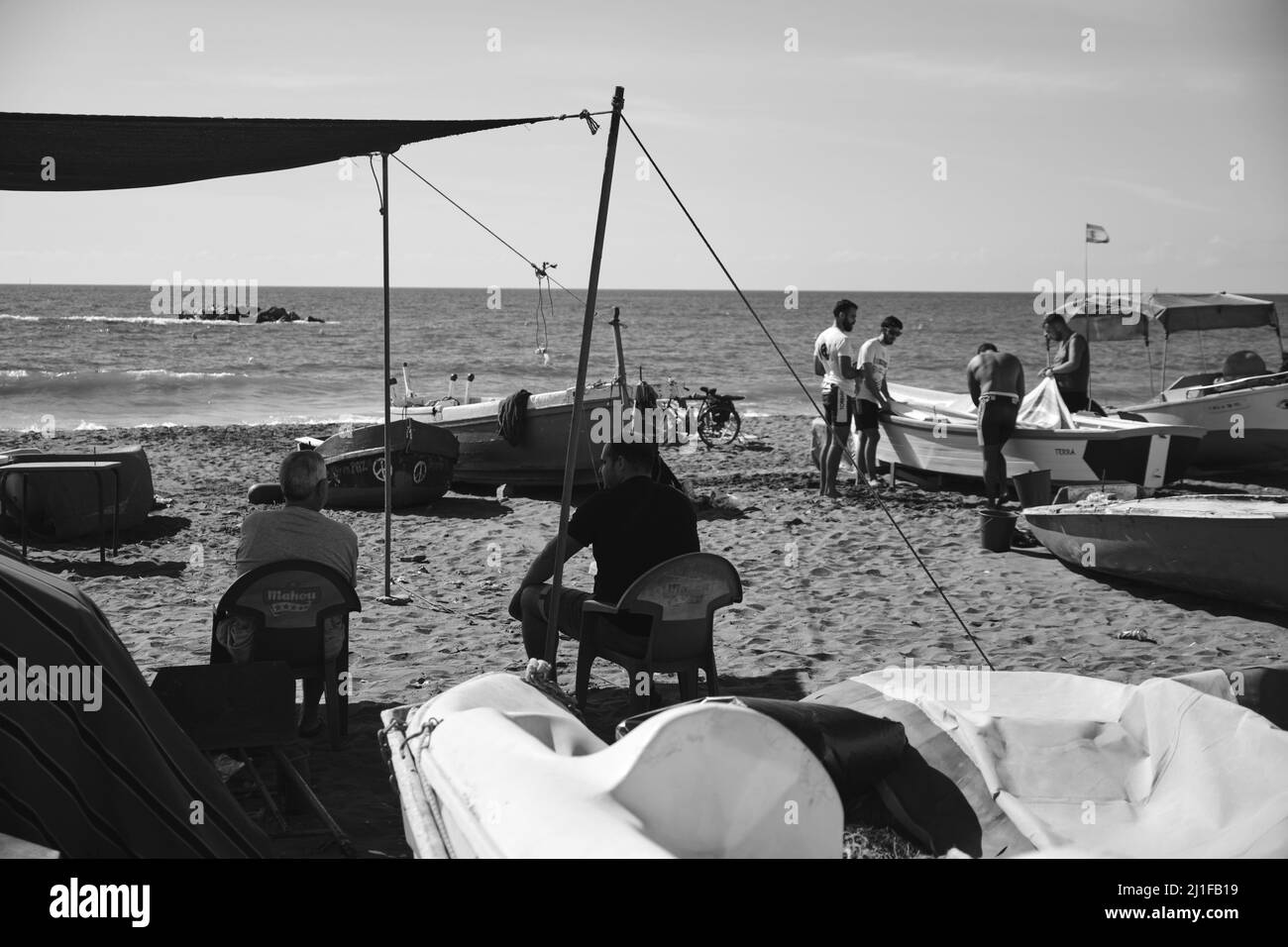 Deux vieux pêcheurs à la retraite qui regardent un groupe de jeunes sur une plage à Malaga, en Espagne Banque D'Images