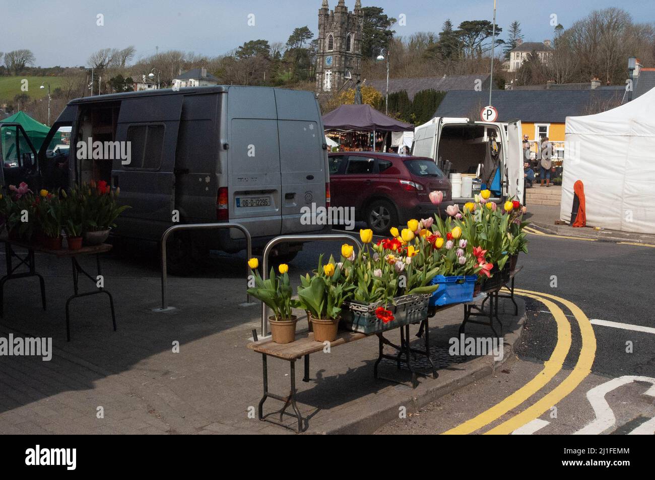 Bantry, West Cork, Irlande, vendredi 25 mars 2022; le soleil se couche aujourd'hui sur le marché de Bantry. Beaucoup de gens où dehors dans les t-shirts avec des températures atteignant 22 degrés. Un stand de fleurs vend des jonquilles lors de la journée annuelle de la Daffodil Society de l'Irish cancer. Credit ED/Alamy Live News Banque D'Images