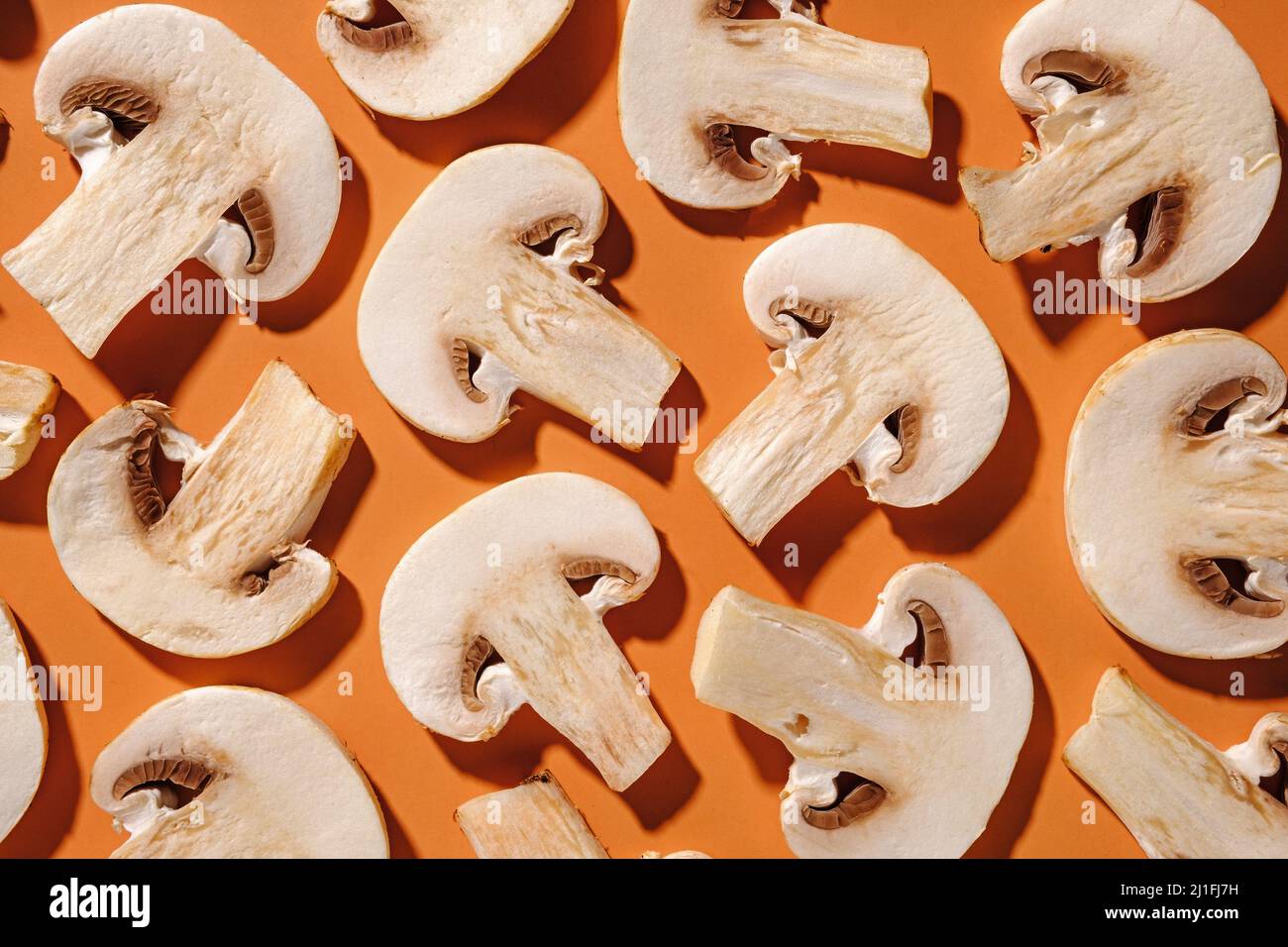 Plat déposer le fond de champignons frais tranchés sur l'orange disposés aléatoirement plein cadre Banque D'Images