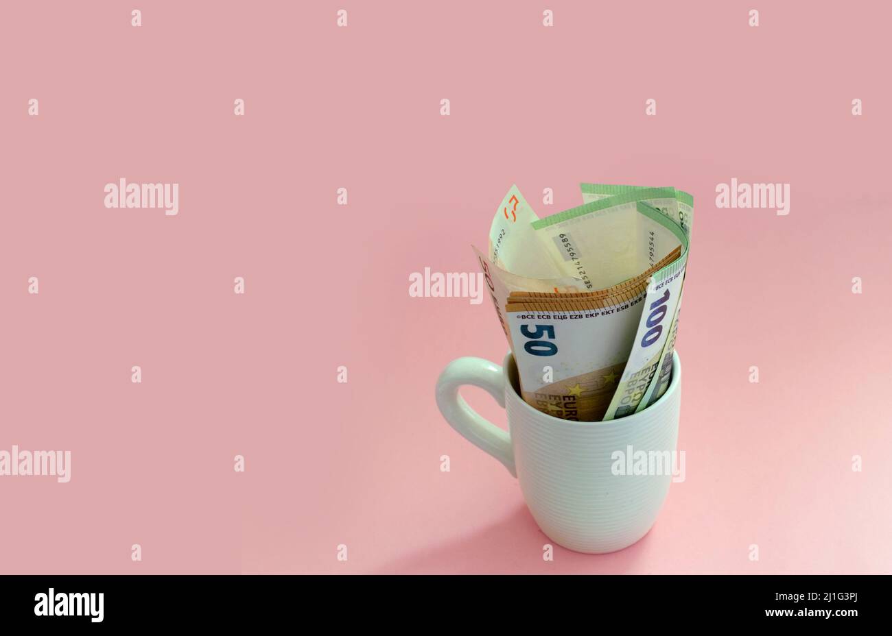 Billets en euros dans une tasse de café sur fond rose. Affaires, finances, échange Banque D'Images