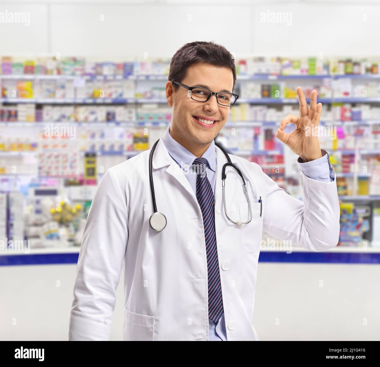 Pharmacien faisant un geste de main OK à l'intérieur d'un magasin de pharmacie Banque D'Images