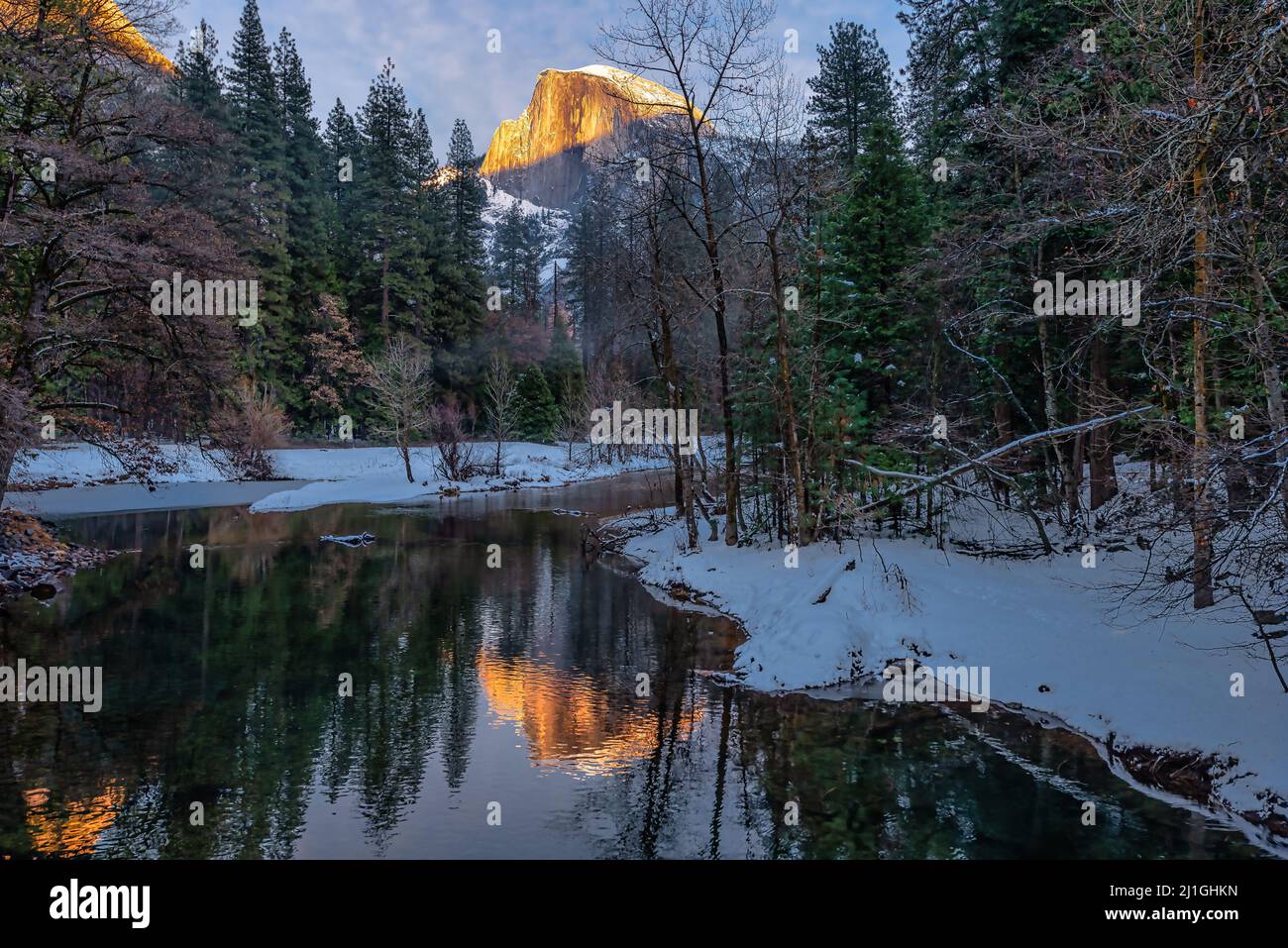 Half Dome illuminé par la lumière du coucher du soleil se reflète sur la rivière Merced en hiver, parc national de Yosemite Banque D'Images