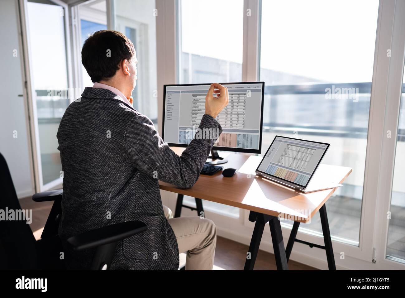 Young Businessman Sitting on Desk In Office Banque D'Images
