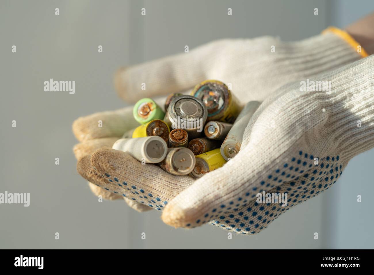 Gros plan des mains des femmes dans des gants de protection en coton tenant le tas de piles alcalines usagées Banque D'Images