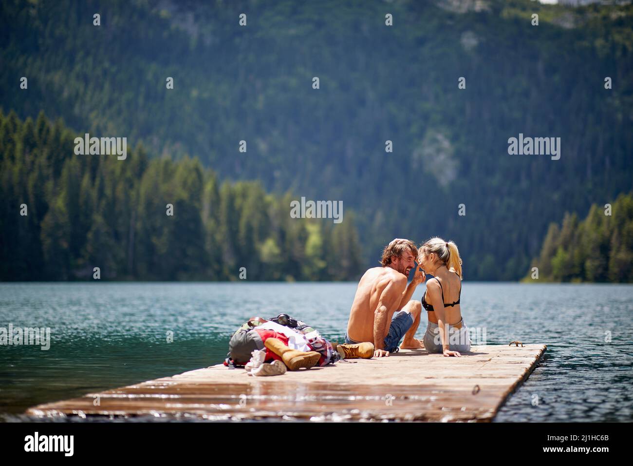 Beau couple amoureux assis sur une jetée en bois au bord du lac. L'amour, l'aventure, la convivialité, le concept de la nature Banque D'Images