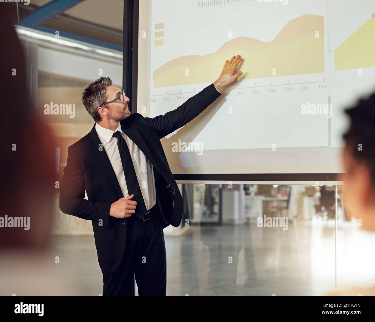 Il connaît ses chiffres. Photo d'un cadre donnant une présentation sur un écran de projection à un groupe de collègues dans une salle de réunion. Banque D'Images