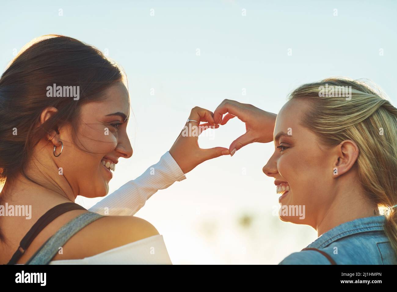Nous adorons voyager mais nous nous aimons davantage. Vue en arrière de deux belles amies féminines en forme de chaleur avec leurs mains dans la nature. Banque D'Images