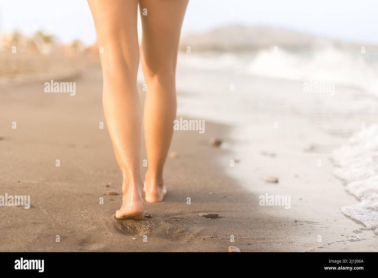 Crop femme marchant sur le sable humide sur le bord de mer Banque D'Images