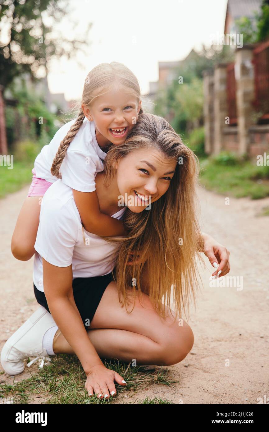 Portrait d'une jeune mère portant sa fille sur le dos. Bonne capuche pour enfant Banque D'Images