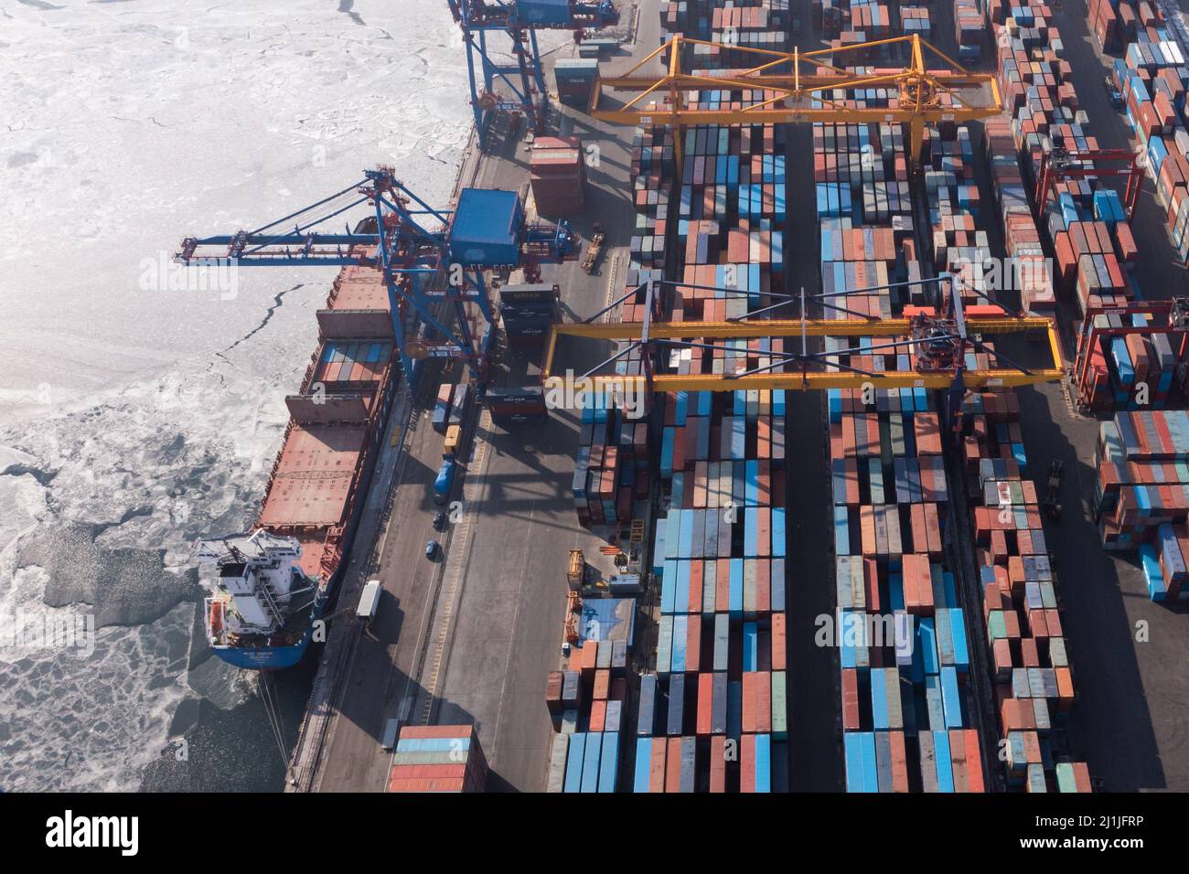 Vladivostok, Russie - 27 janvier 2022 : Vue de dessus du terminal des conteneurs du port maritime. En hiver, un bateau à conteneurs est en train de charger au quai. Banque D'Images