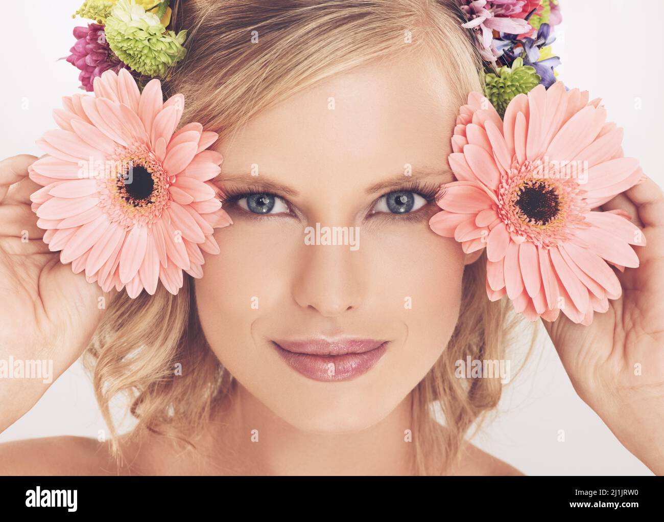 Beauté florale. Une jeune femme avec un arrangement de fleur dans ses cheveux souriant à la caméra. Banque D'Images