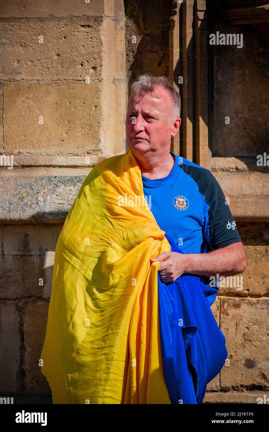 Un homme dans le drapeau ukrainien et le maillot de rugby Bath devant l'abbaye de Bath lors d'une manifestation de solidarité en Ukraine, dimanche 26 mars 2022 Banque D'Images