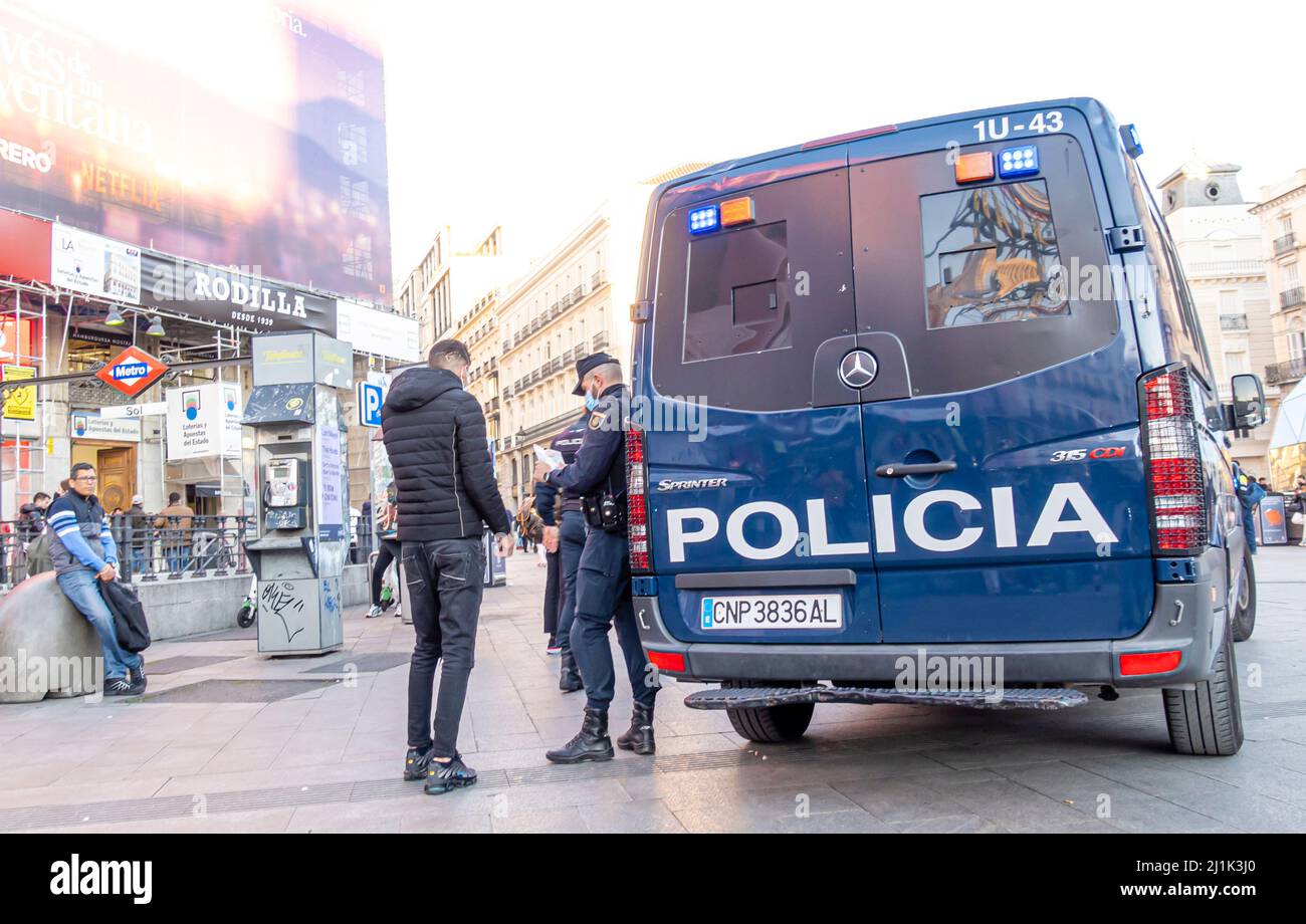 Policia police bleu camionnette espagnole et deux policiers damier les journaux de passersby, place centrale à Madrid, Espagne Banque D'Images