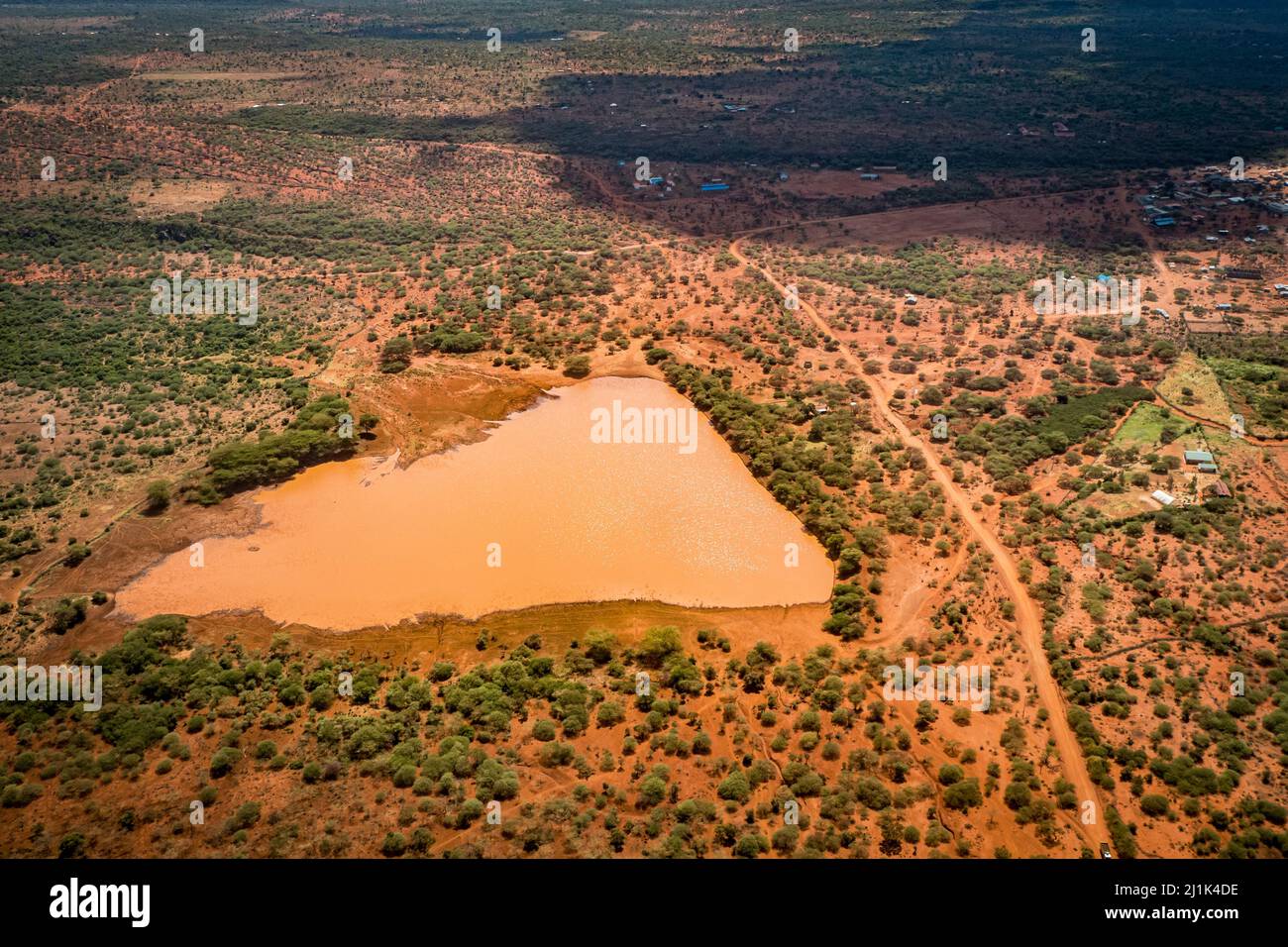 Belle vue aérienne d'un point d'eau orange entouré de sol africain rouge dans la savane du Kenya Banque D'Images