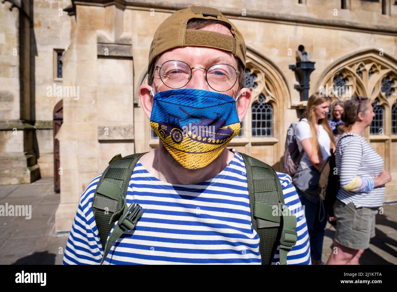 Bath, Royaume-Uni. 26th mars 2022. Un homme portant un masque avec une photo d'un agriculteur ukrainien utilisant un tracteur pour voler un char russe est photographié devant l'abbaye de Bath lors d'une manifestation contre l'invasion de l'Ukraine par la Russie. Les Ukrainiens ont pris sur twitter et facebook pour publier des images et des films sur les agriculteurs ukrainiens utilisant des tracteurs pour remorquer des chars russes et d'autres équipements militaires. En raison de leurs actions, ces agriculteurs ukrainiens ont maintenant gagné un énorme suivi sur les sites de médias sociaux dans le monde entier. Credit: Lynchpics/Alamy Live News Banque D'Images