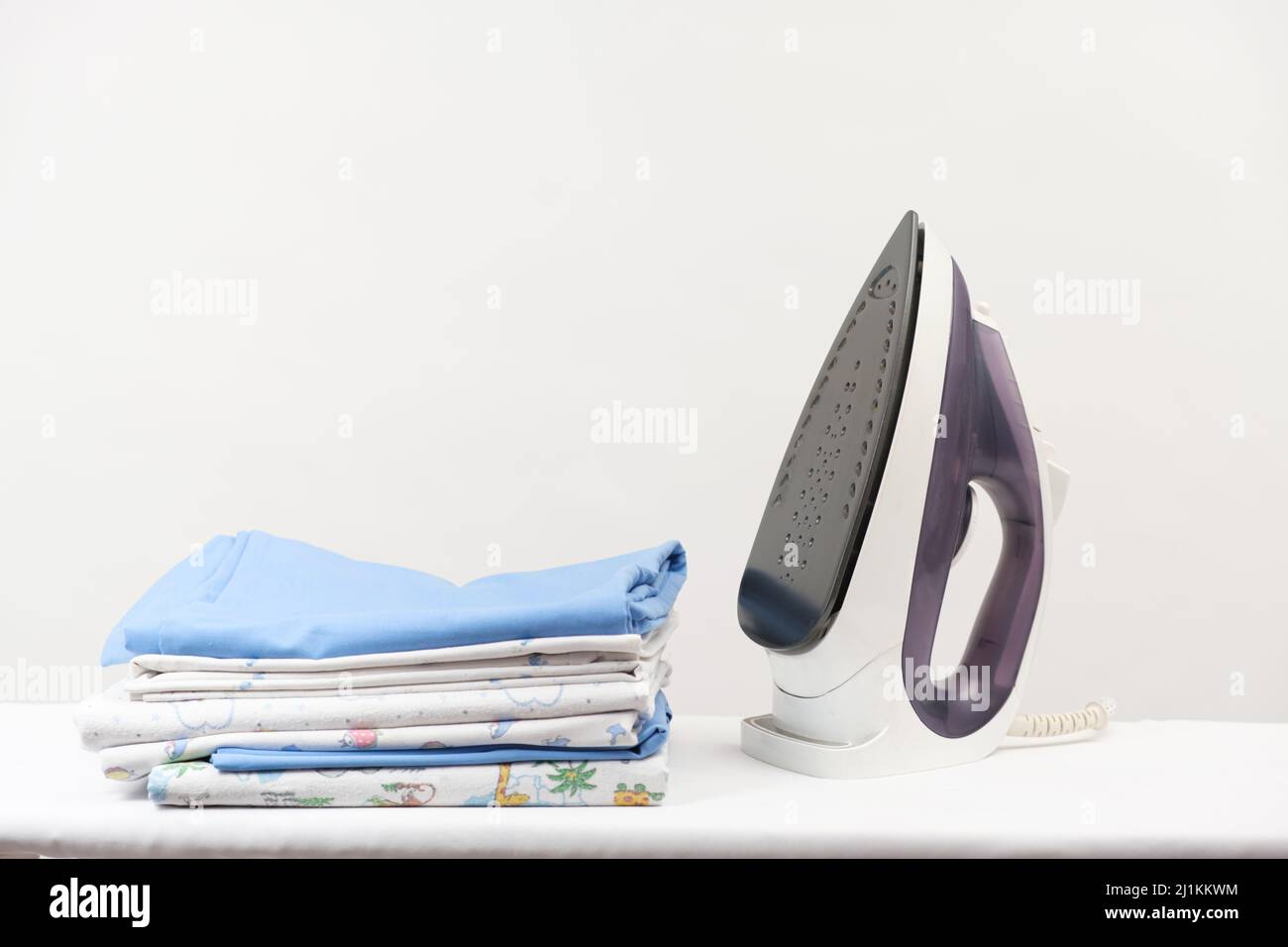 Repassez une pile de vêtements repassés et de couches pour bébé sur un fond blanc avec un espace pour le texte. Banque D'Images